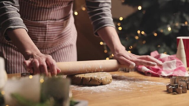 Merry Christmas, Happy New Year. Gingerbread cooking, cake or strudel baking. A young woman or mother rolls out the prepared dough with a rocking chair or wooden rolling pin for cutting out cookies