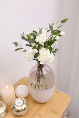 Beautiful flowers and burning candles on wooden dressing table indoors