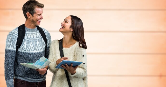Composite image of caucasian couple with map and digital tablet against wooden background