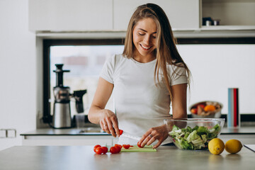 Young woman making salad at the kitchen