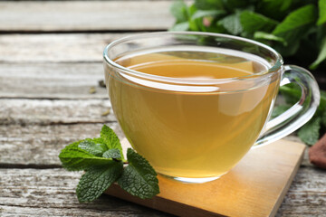 Cup of hot aromatic mint tea on wooden table, closeup
