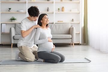 Loving man rubbing his pregnant wife shoulders