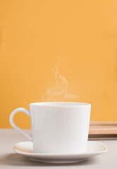 white mug with hot drink, coffee or tea, with orange-yellow background