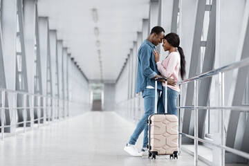 Fototapeta na wymiar Honeymoon Trip. Portrait Of Romantic Black Newlyweds Embracing In Airport Terminal
