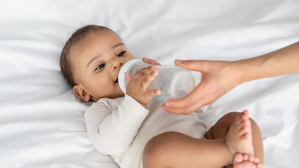 Little African American child drinking from baby bottle
