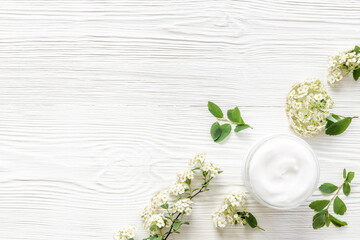 Obraz na płótnie Canvas White blossoms flowers with skin cream in glass jar