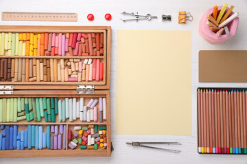 Layout with blank paper, soft pastels and other drawing supplies on white wooden table at artist's workplace, top view. Space for design