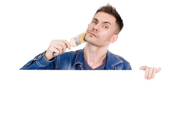 Young guy paints his face with paint brush on isolated white background. Close-up. Copy space.