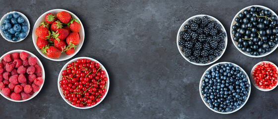 Berries in plates on a black concrete background. Copy space. Flat top view.