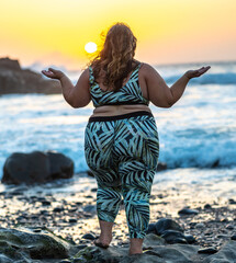 Sehr üppige Frau mit langen Haaren und breiten Hüften beim Yoga vor spektakulärer Meereskulisse...