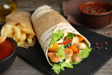 Delicious chicken shawarma on wooden table, closeup