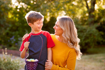 Smiling Mother And Son On Easter Egg Hunt Holding Basket Of Chocolate Eggs Wrapped In Foil