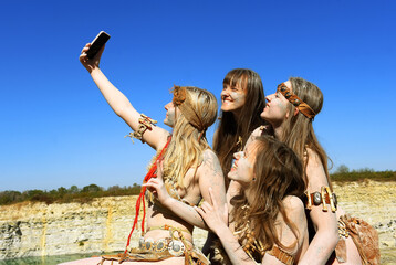 Four girls are dressed up as Neanderthals. One of 
the girls has a mobile phone in her hand and...