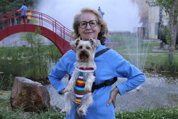 Cute mature woman carrying small dog on chest