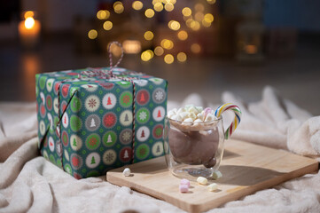 Fototapeta na wymiar Photo of hot chocolate with marshmallows and christmas gift box with bokeh lights on background