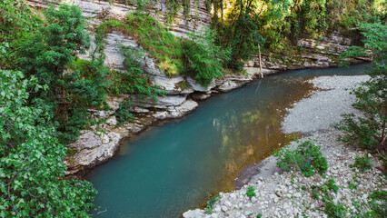 top view of the clear turquoise river flowing among the white rocks and stone banks