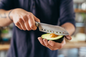 close up man holding knife and avocado