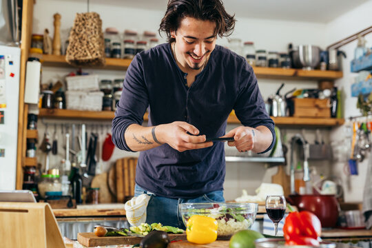 man blogger taking photo of salad in his kitchen