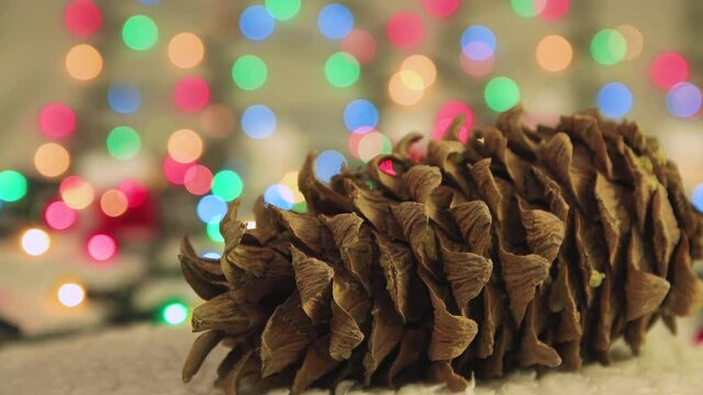 New Year video screensaver pine cone on the background of Christmas lights. Copy space. Multicolored lights out of focus. Beautiful footage, video for intro, transition, intro. UHD 4K.