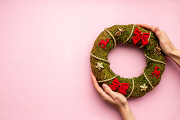 Woman hands holding Christmas wreath with fir tree, top view