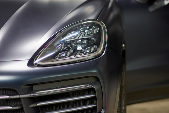 Installation of a protective paint and varnish matte film on a black Porsche Cayenne car. PPF polyurethane film protects car paint from stones, blurred focus. Chelyabinsk, Russia, April 03, 2021
