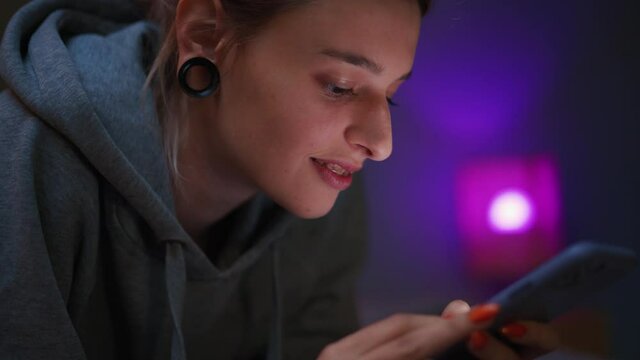 Handsome woman typing by phone on the bed at home