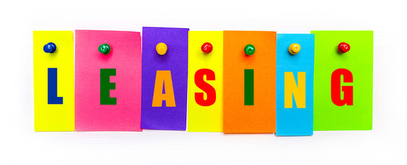 On a white background, buttons are used to fix bright multi-colored strips of paper with the text LEASING