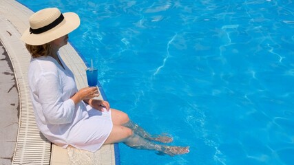 Senior woman relaxing in the hotel swimming pool. People are enjoying their summer vacation. All inclusive