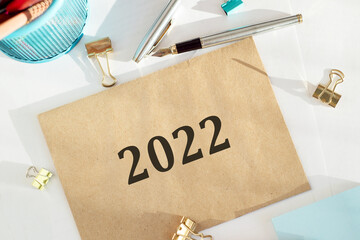 The inscription 2022 on beige envelope on the desk next to office tools