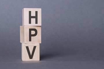 HPV - text, written on wooden blocks, on gray background.