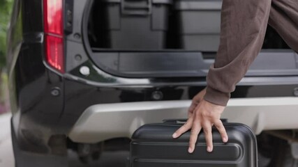 A young man puts his suitcase in the back of the car and prepares to leave. Open the back of the car put luggage travel to other provinces.