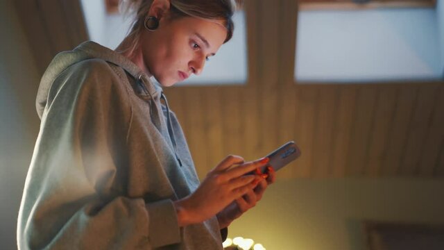 Smiling woman texting on phone in the room at home