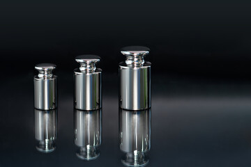 Close-up of weights used for scale calibration on a black background.