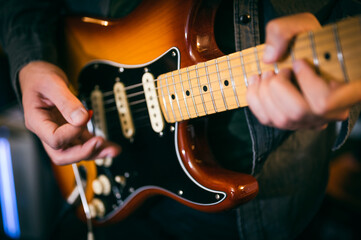 Unrecognizable young man playing electric guitar, close up, selective focus on the strings