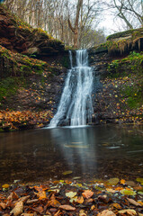 Tranquil waterfall scenery in the middle of autumn forest