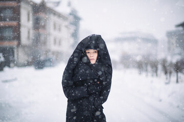 A woman walking down a snowy street - 475360310