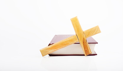 Bible with wooden cross isolated on white background.