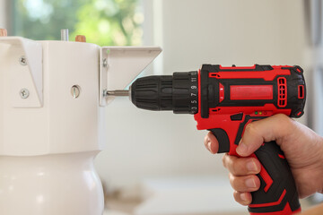 man assembling white table furniture at home using cordless screwdriver