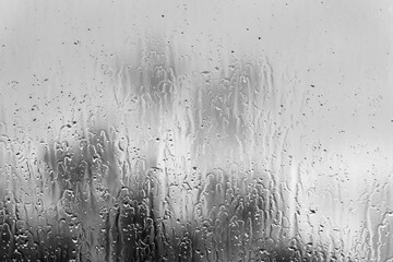 Glass window with rain drops against gray background