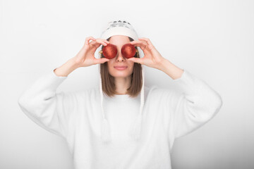 Isolated young girl holding 2 Christmas balls near her eyes