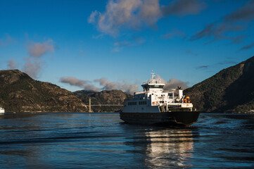 Beautiful landscape of huge rocks and Lusefjord. Bridge over the fjord. A floating ship.