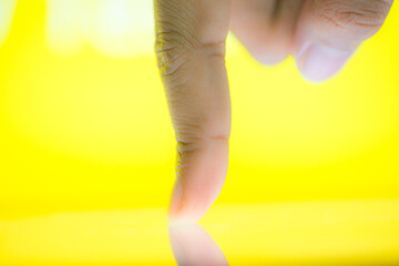 Male hand holds a smartphone, points a finger types. Communication on a smartphone, correspondence. Smartphone in hand on a yellow background 