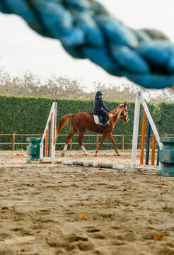 Kid learning horseback riding with obstacles at the ranch.