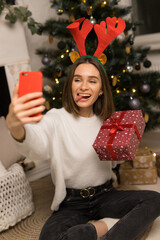 Close up of young girl telephone to parents and show a red Christmas gift and her tongue