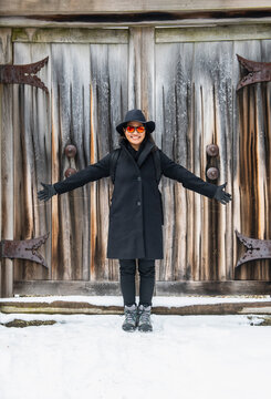 beautiful woman standing in front of a closed wooden gate
