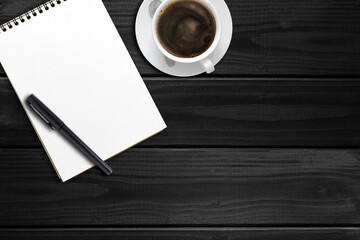 notebook, pen and cup of coffee on a wooden dark table, view from the top