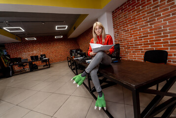 Creative woman sitting at the desk in her modern office interior while looking at the documents and working. Program development concept