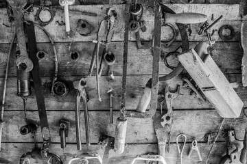 Workshop scene. Old tools hanging on wall in workshop, Tool shelf against a table and wall, vintage garage style black and white
