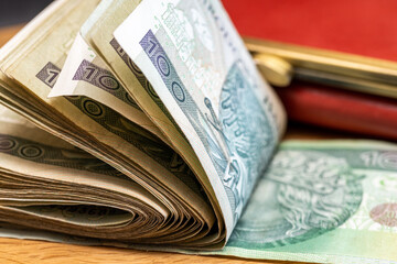 thick bundle of folded 100 zloty banknotes from Poland, table, wallet, close-up