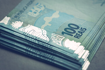 Obraz premium Large bundle of Brazilian money, 100 reais banknotes, gray background
